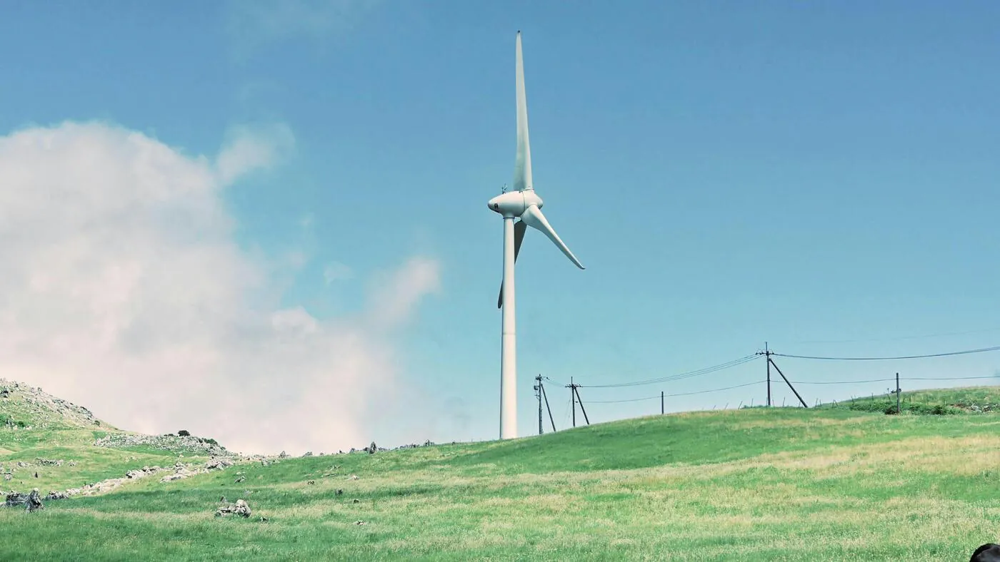 Wind turbine on a hillside under a blue sky